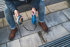 Close-up photo of man's hands holding pet collar with a leash. width=